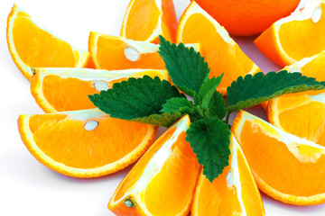 Macro view of orange with sections and green leaf of mint on white background - 373458165