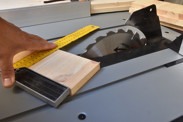 falegname all'opera su una sega circolare. L' artigiano sta misurando per un taglio preciso ed ortogonale