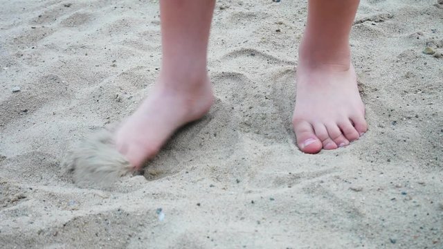 Two feet of a little boy marking time on the sand place