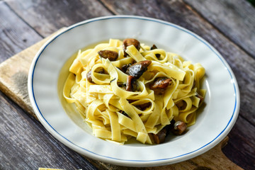 Italian food . Fresh home made  tagliatelle vegetarian  egg pasta  with mushrooms ,parmesan cheese ,fresh parsley  and black pepper.