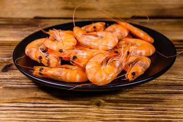 Plate with raw shrimps on a wooden table