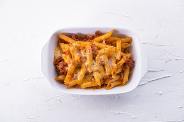 Macaroni bolognesa with minced meat, tomato sauce and gratin cheese on white background. Italian cuisine. Top view.