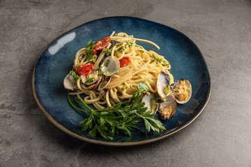 Plate of spaghetti with clams, courgettes, tomatoes and parsley. Italian recipe. Italian seafood cuisine.