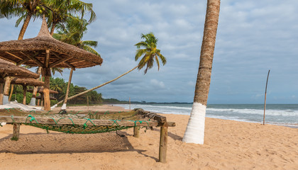 Africa tropical beach with palm trees and sun loungers standing empty, The beach is located on Ghana's gold coast Axim