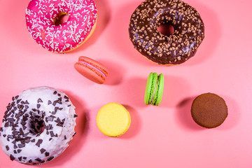Fresh glazed donuts and french macaroons isolated on a pink background