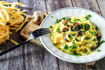 Italian food . Fresh home made  tagliatelle vegetarian  egg pasta  with mushrooms ,parmesan cheese ,fresh parsley  and black pepper.
