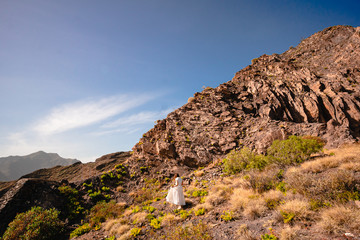 Fototapeta na wymiar a girl in a white dress goes up a mountain