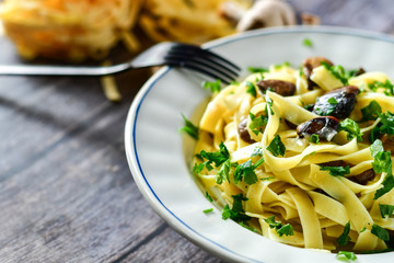 Italian food . Fresh home made  tagliatelle vegetarian  egg pasta  with mushrooms ,parmesan cheese ,fresh parsley  and black pepper.