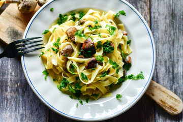Italian food . Fresh home made  tagliatelle vegetarian  egg pasta  with mushrooms ,parmesan cheese ,fresh parsley  and black pepper.