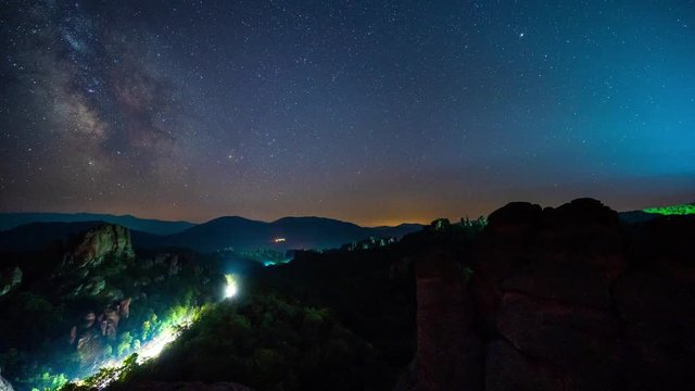 Amazing night time lapse with Milky Way galaxy, traffic lights, plane trails and meteor shower, during Perseid Stream over picturesque rock formation, Belogradchik rocks, Bulgaria