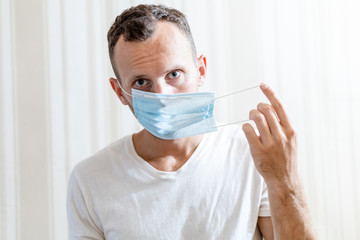 young man putting on a medical mask on his face