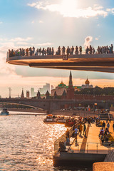 Naklejka premium Floating bridge with people above Moskva River in Zaryadye Park, Moscow, Russia in summer in sunset