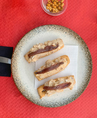 VIEW OF THE TOP OF A PLATE WITH BUTTER AND ON TOP IT HAS RUSSIAN SALAD AND AN ANCHOVY