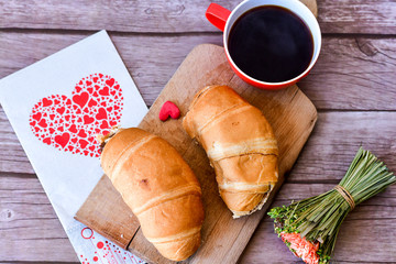  Fresh baked croissant and cup of coffee with red hearts. Romantic breakfast