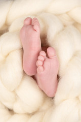 Bare feet of a cute newborn baby in warm white blanket. Childhood. Small bare feet of a little baby girl or boy. Sleeping newborn child.