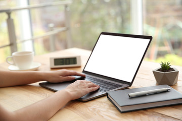 Woman working with modern laptop at wooden table, closeup