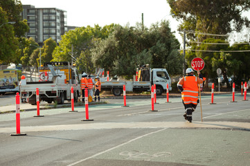 Melbourne, Victoria / Australia - January 2 2020: Traffic control worker is holding stop sign to stop the traffic near Caulfield train station. © Olha