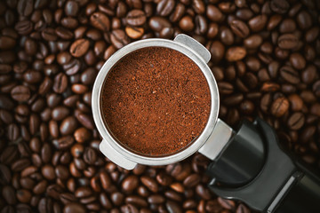 Against the background of fragrant roasted coffee beans is a holder filter from the coffee maker, in which ground coffee. It will make an invigorating espresso. Coffee house.