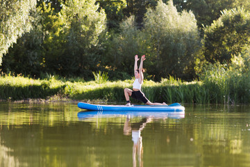 Fototapeta na wymiar woman doing yoga on sup board at sunset. outdoor summer activity. Sup yoga. Social Distancing. copy space. Mental Health