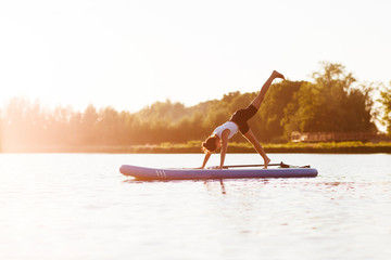 woman doing yoga on sup board at sunset. outdoor summer activity. Sup yoga.  Social Distancing....