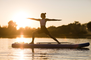 woman doing yoga on sup board at sunset. outdoor summer activity. Sup yoga.  Social Distancing....