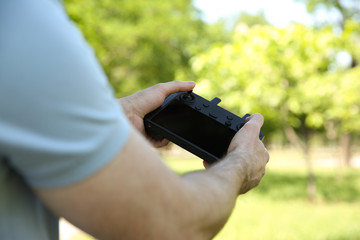 Man holding new modern drone controller outdoors, closeup of hands
