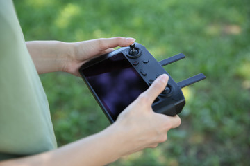 Woman holding new modern drone controller outdoors, closeup of hands