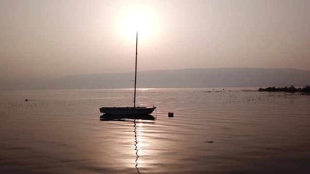 Sunrise over the lake. Boat floating on the calm water under amazing sunset.