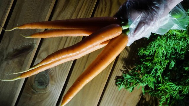 4k. A row of red carrots with green leaf on a rotating wooden table.