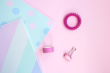 Two bright sketchbooks, scotch tape, pink clip and hair tie on a pink background. Stationery on a pink background with space for text. Back to school, creative workspace. Flat lay