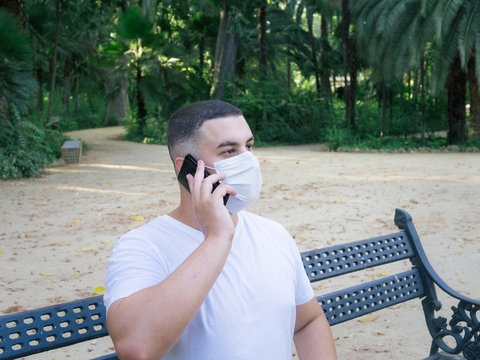 Closeup shot of a male holding a phone wearing a sanitary mask - concept of the new normal