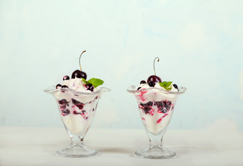 Whipped cream dessert with cherries and currants, garnished with mint leaves on a light blue background. Healthy eating. Organic products.