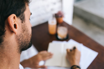 Cropped image of man writing in notepad on work process, close up view of bearded caucasian male...