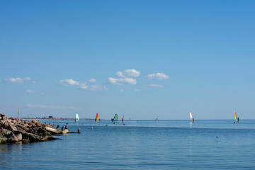 sea view on a sunny summer day, windsurf sails and white clouds on the horizon