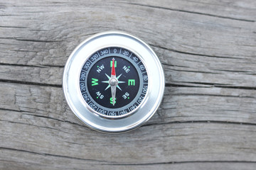 round compass on natural wooden background as symbol of tourism with compass, travel with compass and outdoor activities with compass