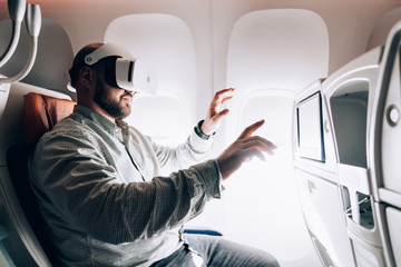 Man enjoying virtual reality in modern VR headset in airplane