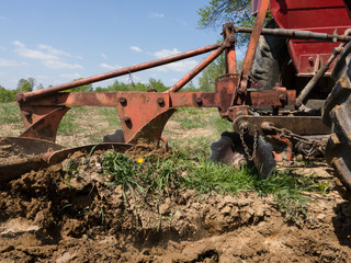 Tillage of agricultural machinery, soil preparation for sowing. Tractor and plow in the field during a sunny day.