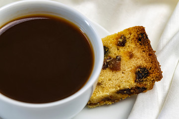 a cup of coffee and a piece of muffin breakfast in bed close up