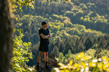 Trail runner stands on a rock in the mountains