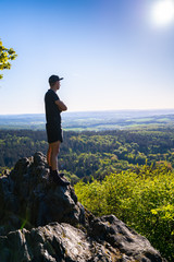 Obraz premium Trail runner stands on a rock in the mountains