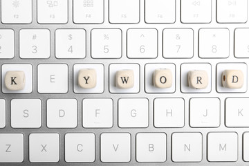Beads with word KEYWORD on keyboard, flat lay