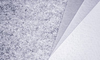 Close up of pieces of felt of different shades of grey from dark to very light. Gray spectrum. Copy space. On the left, on a light grey background - a place for text