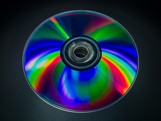 Rainbow colors on the underside of a cd or dvd against a dark background.