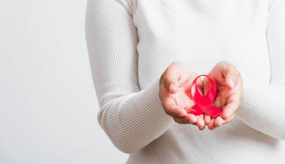 Breast cancer awareness healthcare and medicine concept. Close up Asian woman holding pink breast cancer awareness ribbon on hands treatment charity, studio shot isolated on white background