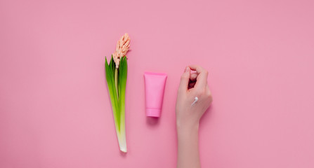 Female hands with hand cream and flowers. Top horizontal view copyspace. Hand care and beauty
