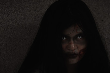 Girl zombie in blood. Asian Woman ghost with blood. Horror creepy scary fear she sitting in a dark house. Hair covering the face, Halloween festival concept