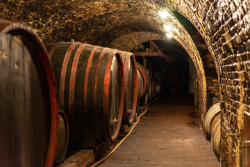wooden old barrels in the rustic wine cellar with brick walls in villany hungary