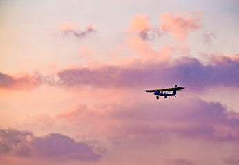 Fototapeta na wymiar silhouette of ultralight microlite aircraft flying with a pilot and a passenger against sunset sky.