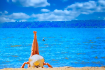 young woman wearing a hat relaxing on the beach