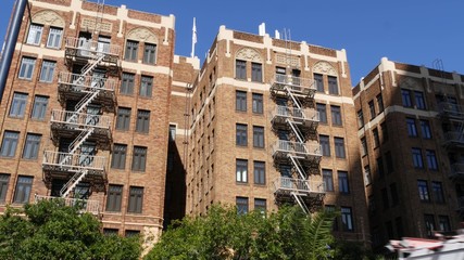 Fire escape ladder outside residential brick building in San Diego city, USA. Typical New York style emergency exit for safe evacuation. Classic retro house exterior as symbol of real estate property